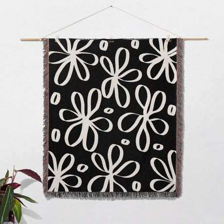 Black and white modern artsy flowers woven blanket throw hanging on a wall as a wall tapestry. 