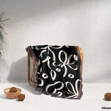 Black and white modern artsy flowers woven blanket throw draped over a chair against a light gray wall.