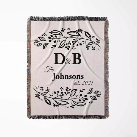 Monogrammed cotton throw blanket perfect engagement and wedding gift flat lay on a white background