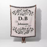 Monogrammed cotton throw blanket perfect engagement and wedding gift held by a person on a white background