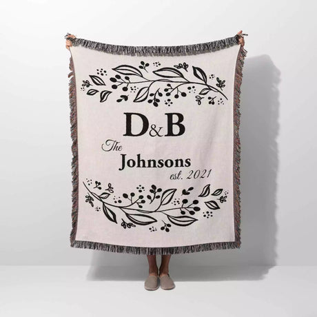 Monogrammed cotton throw blanket perfect engagement and wedding gift held by a person on a white background