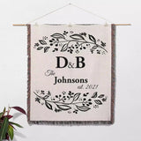 Monogrammed cotton throw blanket perfect engagement and wedding gift hanging on a wall on a white background.