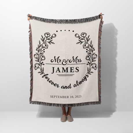 Mr and Mrs cotton wedding anniversary gift woven blanket with floral design and text held by a person on a white background