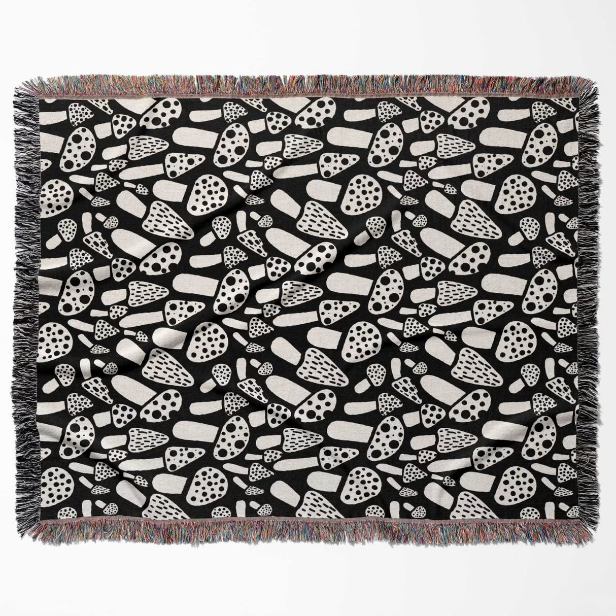 Black and white mushrooms patterned woven blanket throw flat lay on a white background.