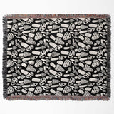 Black and white mushrooms patterned woven blanket throw flat lay on a white background.
