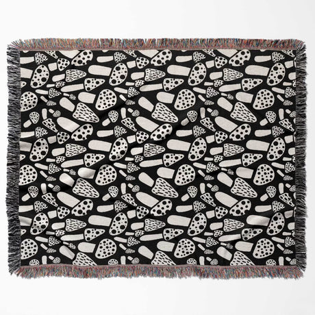 Black and white mushrooms patterned woven blanket throw flat lay on a white background.