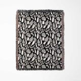 Black and white mushrooms patterned woven blanket throw full view on a light gray background.
