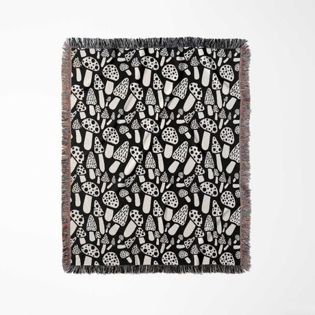 Black and white mushrooms patterned woven blanket throw full view on a light gray background.