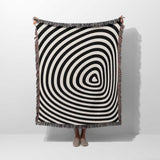 Black and white optical illusion hole woven blanket throw tapestry held by a person on a white background.