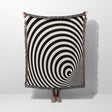Black and white optical illusion wormhole woven blanket throw tapestry draped over a person on a white background.