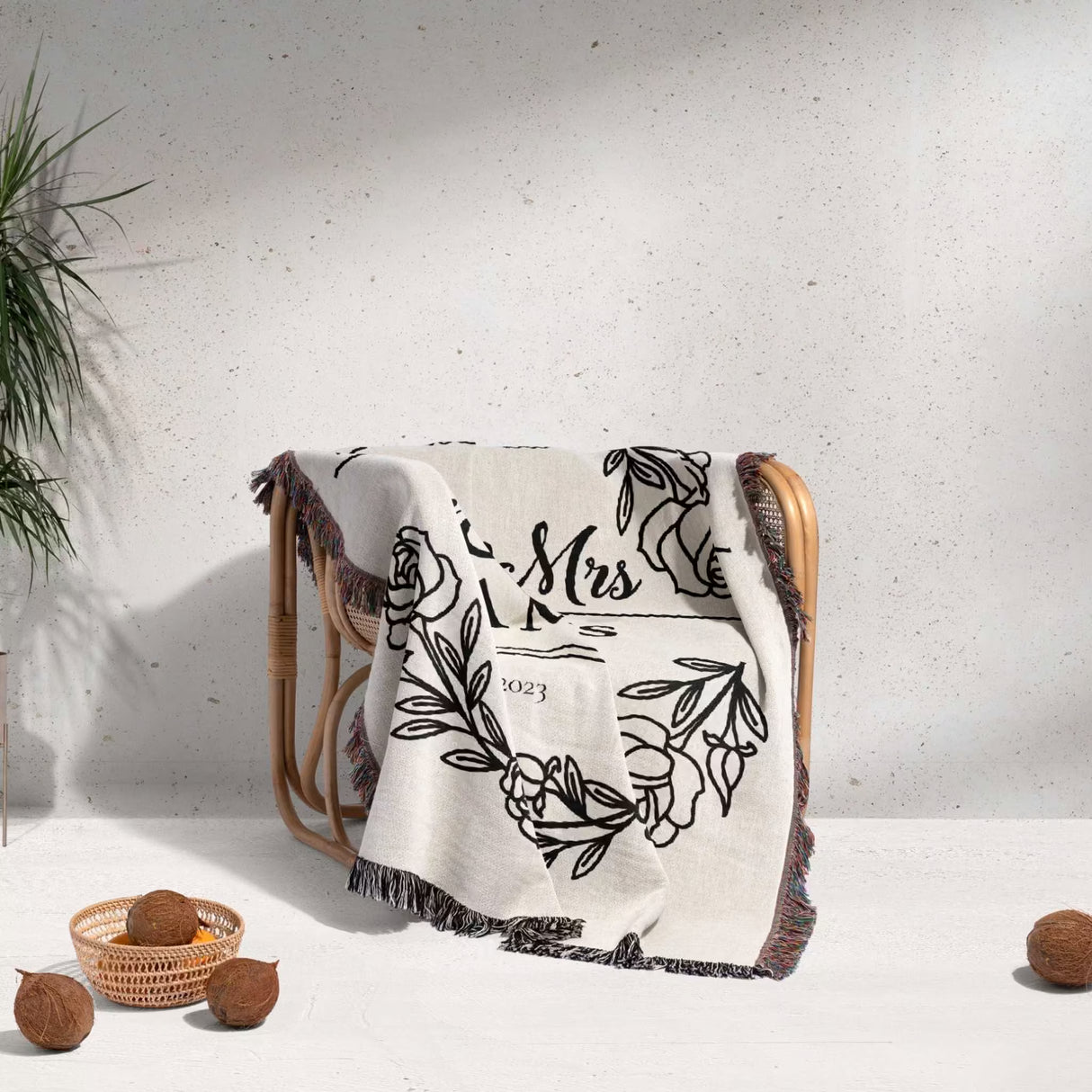 Personalized 2 year anniversary gift - Mr and Mrs woven throw blanket with floral design and 'Mrs' text draped over a chair against a white wall.