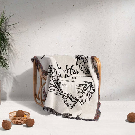 Personalized 2 year anniversary gift - Mr and Mrs woven throw blanket with floral design and 'Mrs' text draped over a chair against a white wall.