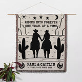 Personalized cowboy and cowgirl cotton anniversary gift woven throw blanket with cowboy design and text, hanging on a wall.