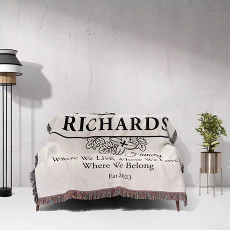 Personalized family name blanket - new home unique housewarming gift with 'Richards Family' text draped over a couch against a white wall.