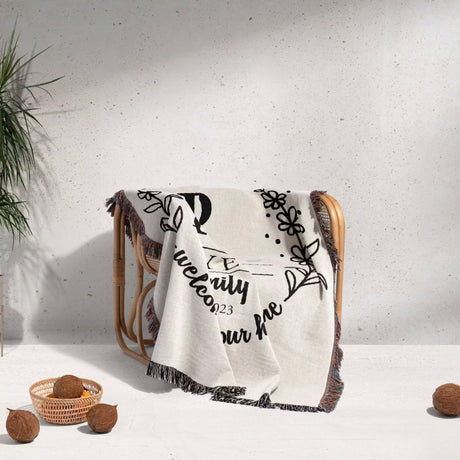 Personalized family name woven blanket rustic home décor gift with text and patterns draped over a chair on a light background