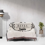 Personalized family name woven blanket rustic home décor gift with 'REYES family' text draped over a couch against a light gray wall.