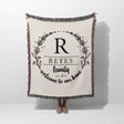 Personalized family name woven blanket rustic home décor gift with 'REYES family welcome to our home' text hold by a person on a white background
