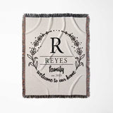Personalized family name woven blanket rustic home décor gift with 'Reyes family, welcome to our home' text flat lay on a white background