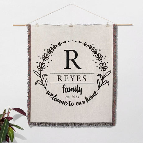 Personalized family name woven blanket rustic home décor gift wall hanging with 'REYES family welcome to our home' text on a white background