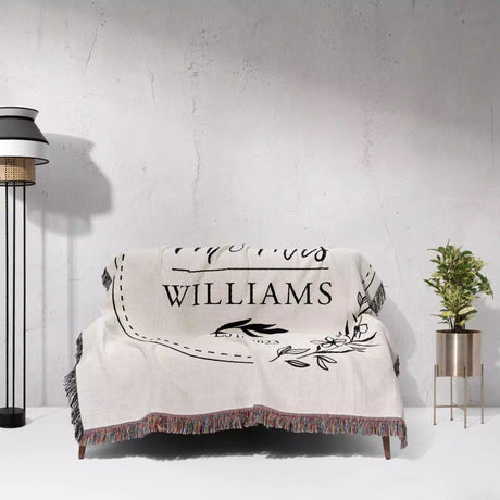 Personalized mr and mrs blanket with 'Williams' text draped over a chair against a white wall.