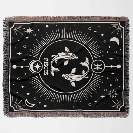 A flat horizontal image of the Pisces Zodiac Blanket showcasing the intricate black and white design. The blanket features two fish, a symbol of the Pisces zodiac, surrounded by celestial elements and detailed fringe edges.