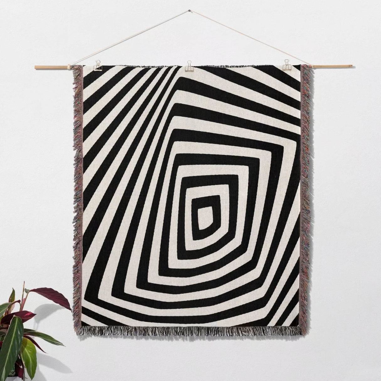 Psychedelic abstract art woven blanket throw tapestry with concentric circles on a white wall.