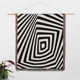 Psychedelic abstract art woven blanket throw tapestry with concentric circles on a white wall.