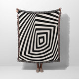Psychedelic abstract art woven blanket throw tapestry with a person partially visible underneath on a white background.