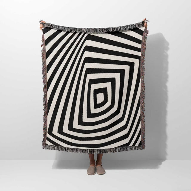 Psychedelic abstract art woven blanket throw tapestry with a person partially visible underneath on a white background.