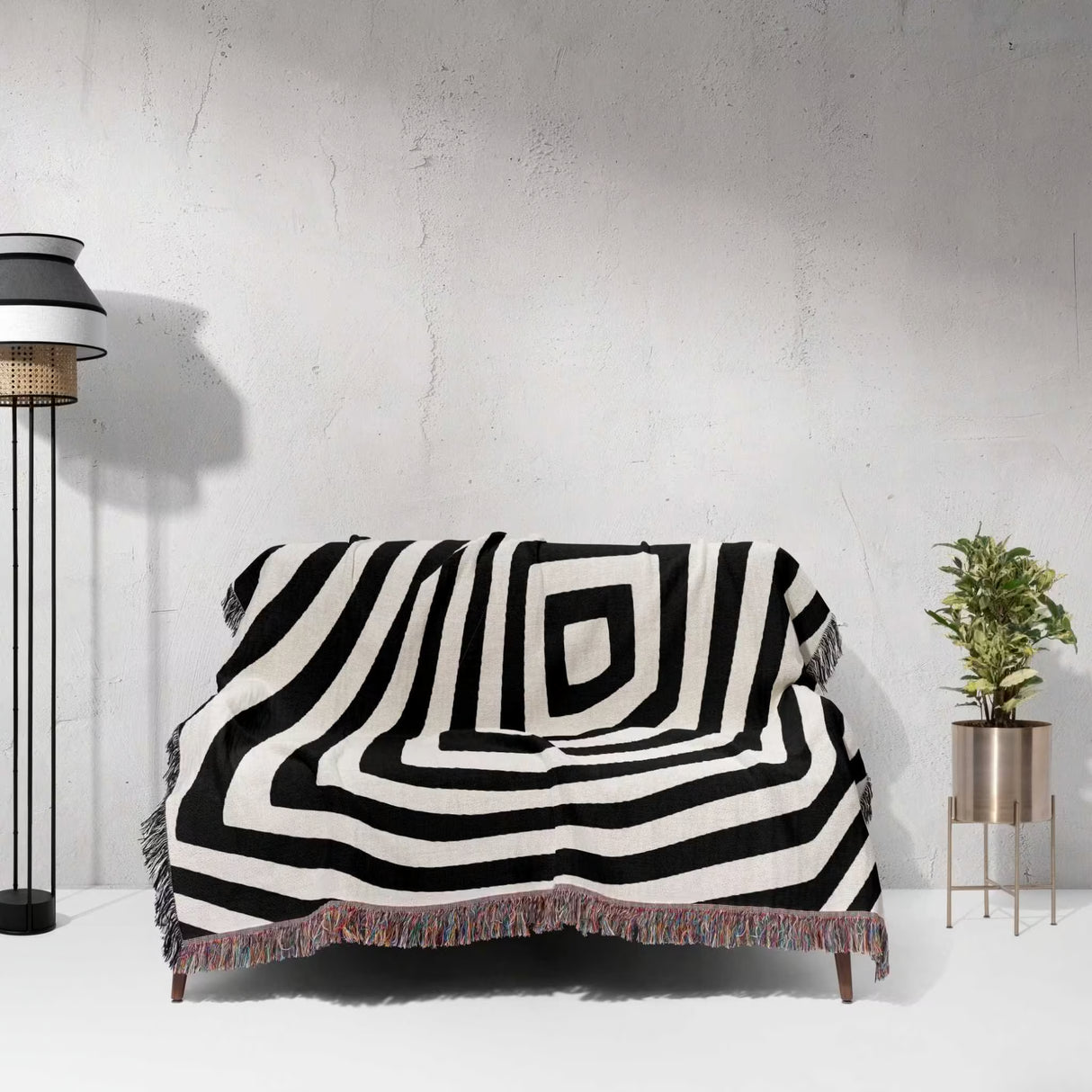 Psychedelic abstract art woven blanket throw tapestry draped over a couch against a white wall.