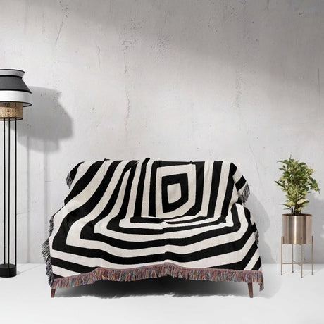Psychedelic abstract art woven blanket throw tapestry draped over a couch against a white wall.