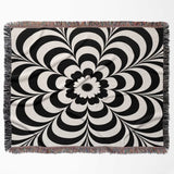 Black and white psychedelic flower woven blanket throw tapestry with fringed edges horizontal flat lay on a white background.