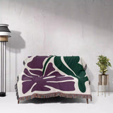 Floral-patterned purple Matisse flowers woven throw blanket draped over a chair against a white wall.