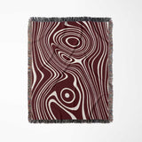 Red abstract woven throw blanket with a swirling pattern on a white background