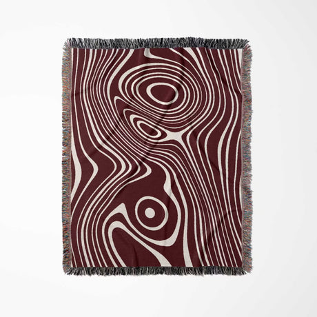 Red abstract woven throw blanket with a swirling pattern on a white background
