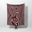 Person holding a patterned red abstract woven throw blanket with concentric circle design on a white background