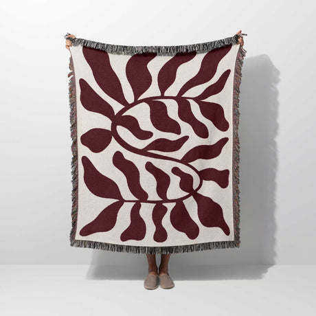 Red leaf Matisse throw blanket held by a person on a white background