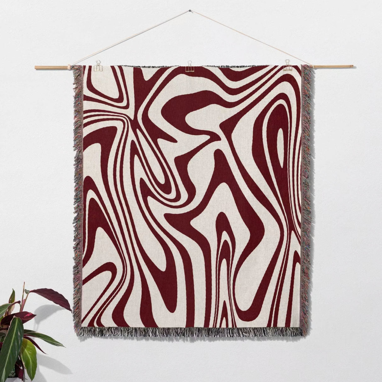 Red marble woven throw blanket for couch with abstract pattern hanging on a white wall