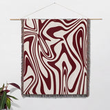 Red marble woven throw blanket for couch with abstract pattern hanging on a white wall