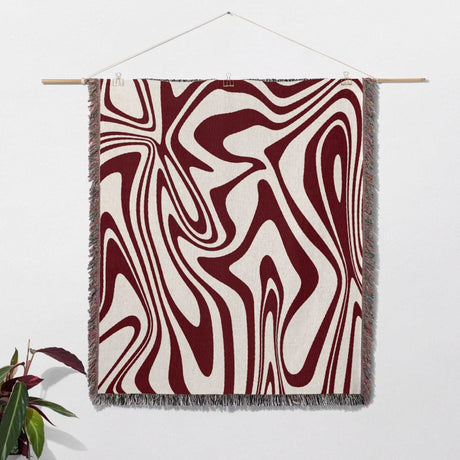 Red marble woven throw blanket for couch with abstract pattern hanging on a white wall