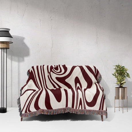 Sofa with a patterned red marble woven throw blanket for couch against a white wall.