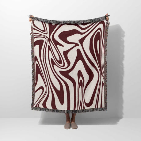 Red marble woven throw blanket for couch with abstract pattern hold by person on a white background