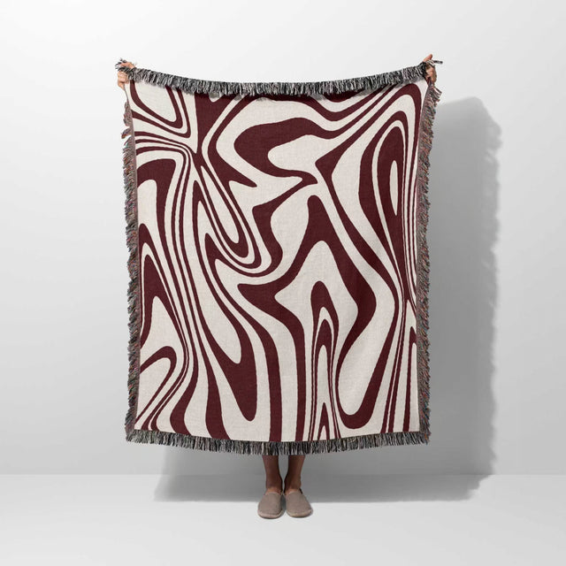 Red marble woven throw blanket for couch with abstract pattern hold by person on a white background