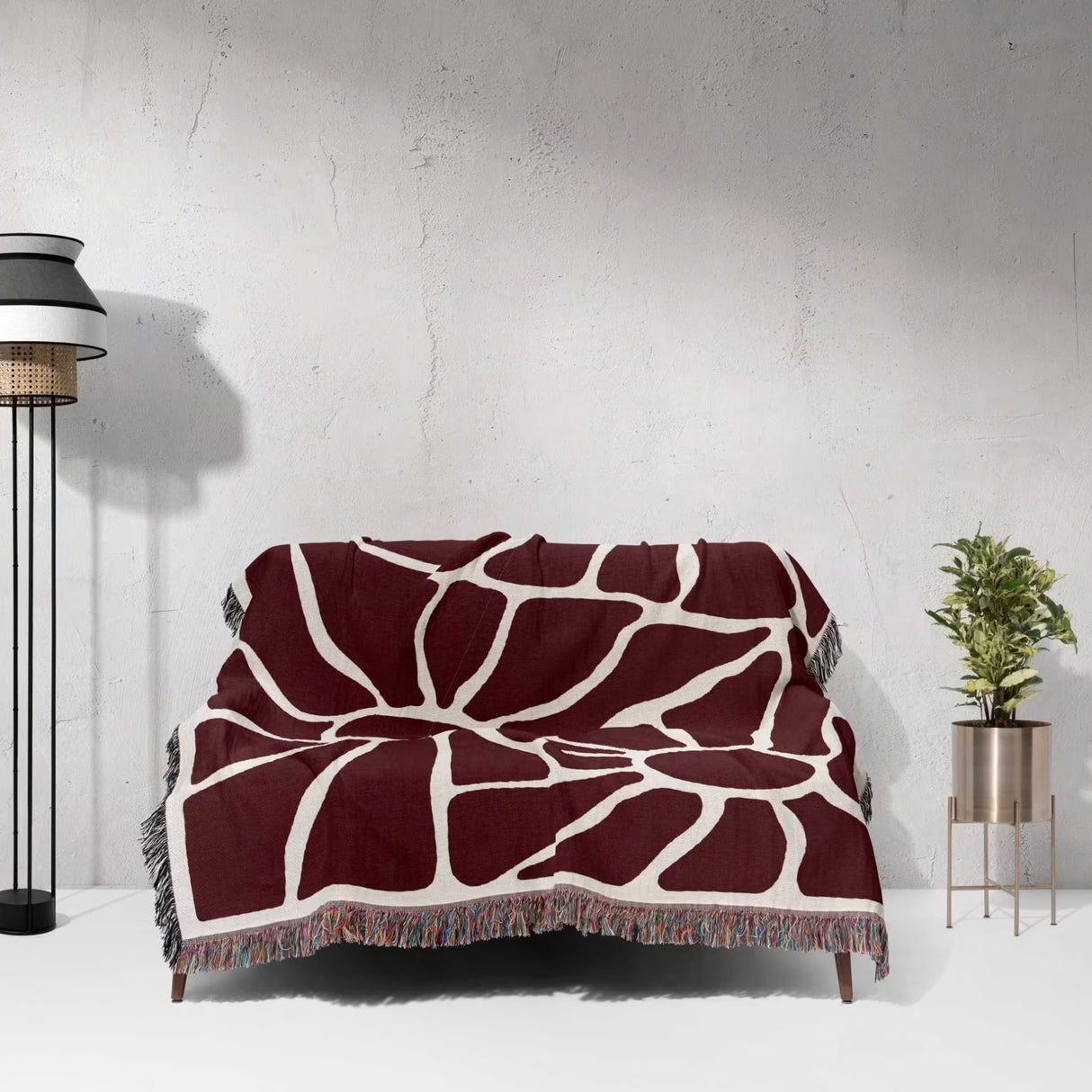Red Matisse tapestry throw blanket for couch and chair draped over a couch against a white wall.
