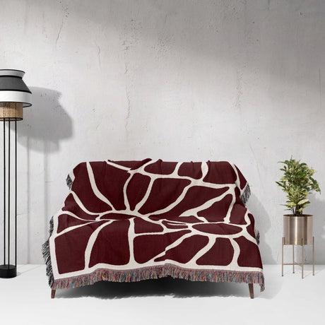Red Matisse tapestry throw blanket for couch and chair draped over a couch against a white wall.