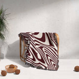 Red modern decorative woven throw blanket with abstract pattern draped over a chair against a light background