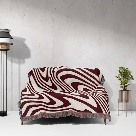 Sofa with a red modern decorative woven throw blanket in a minimalistic room.