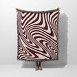 Red modern decorative woven throw blanket with a swirling pattern draped over a person on a white background