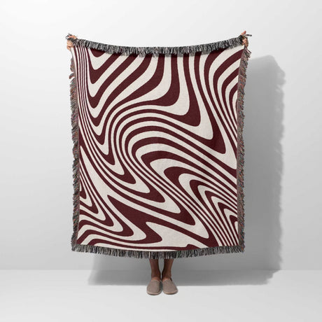 Red modern decorative woven throw blanket with a swirling pattern draped over a person on a white background