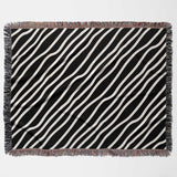 Black and white retro abstract art woven blanket throw tapestry with fringed edges flat lay on a light gray background